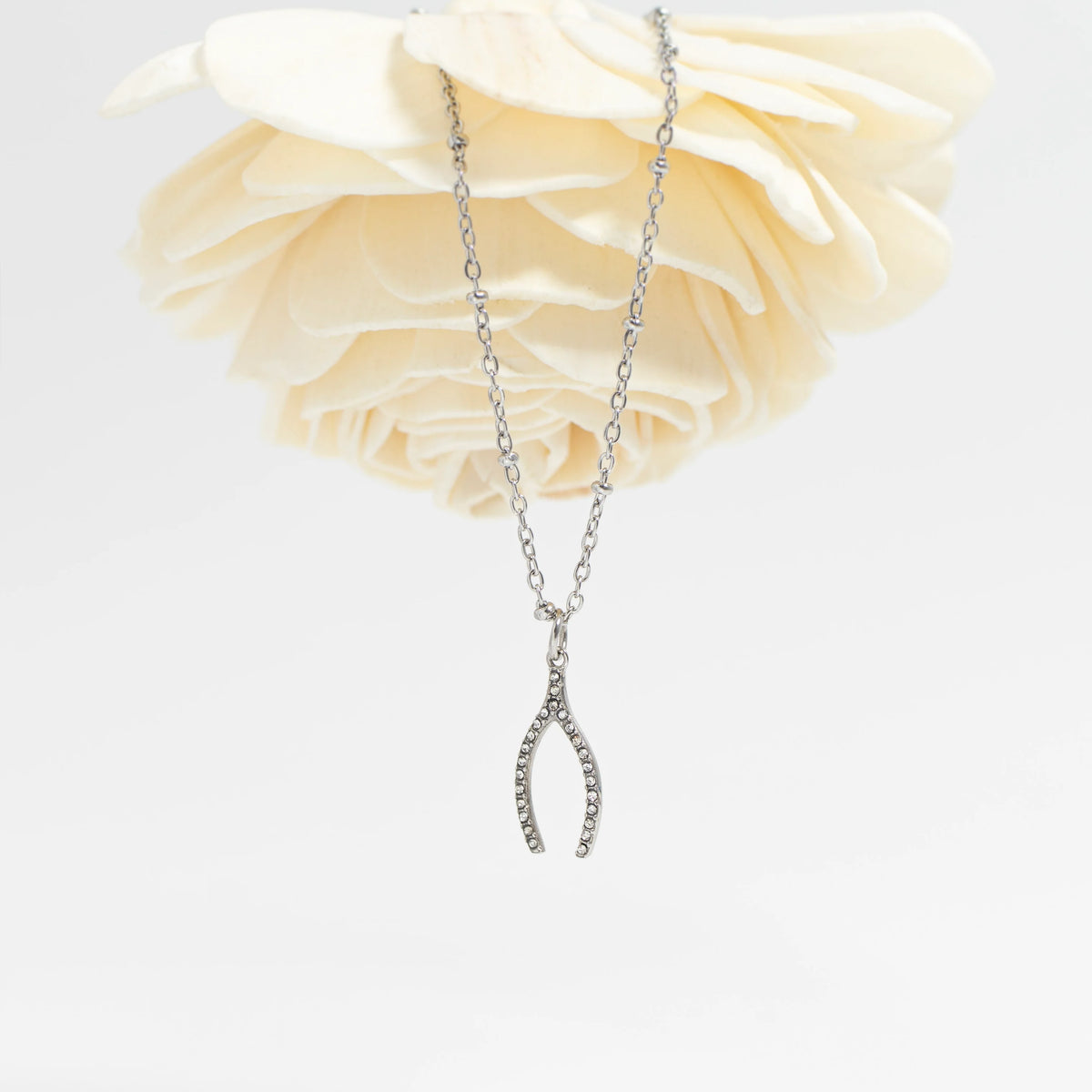 ORRÉ Rhinestone Wishbone Charm in silver — styled jewelry photograph