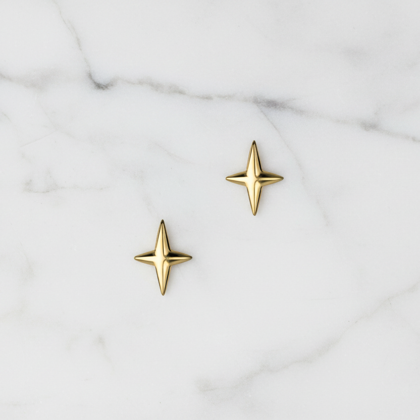 Gold star-shaped earrings on a marble surface