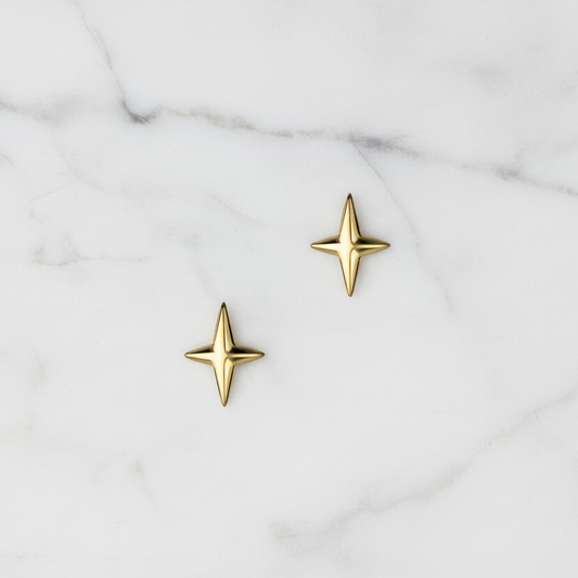 Gold star-shaped earrings on a marble surface